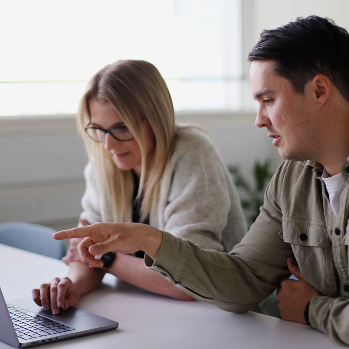 CleanManager-kollegaer sidder sammen ved en computer og samarbejder om en opgave.